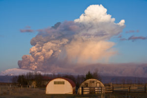 Farm and erupting Eyjafjallajokull glacier in the 2010 eruption of Eyjafjallajokull volcano on the south coast of Iceland