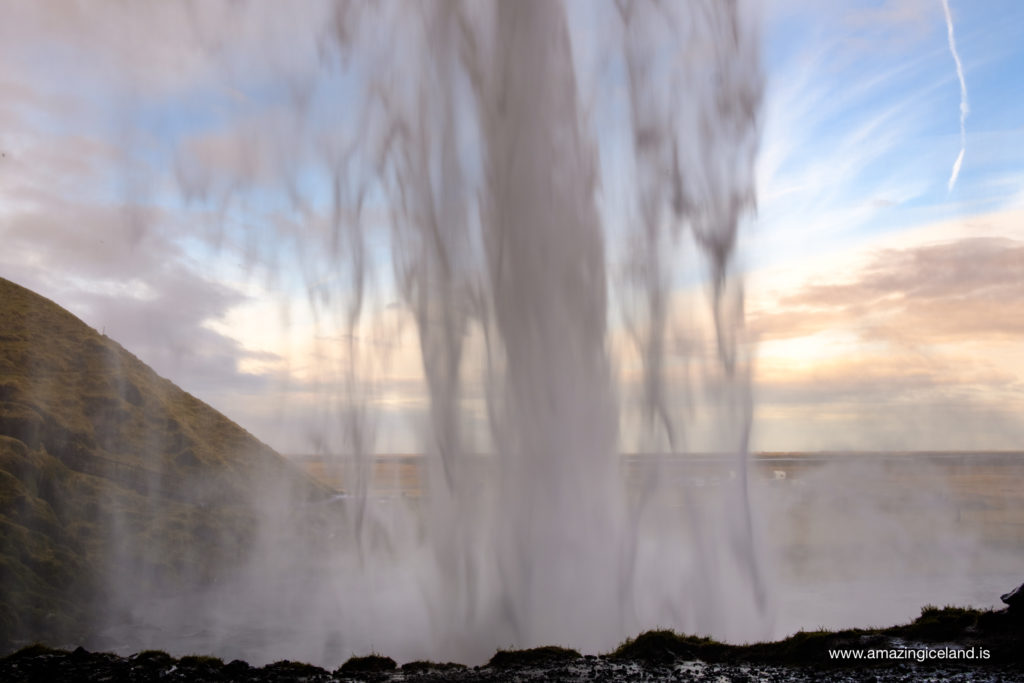 Enjoying view behind Seljalandsfoss waterfall on the south coast of Iceland