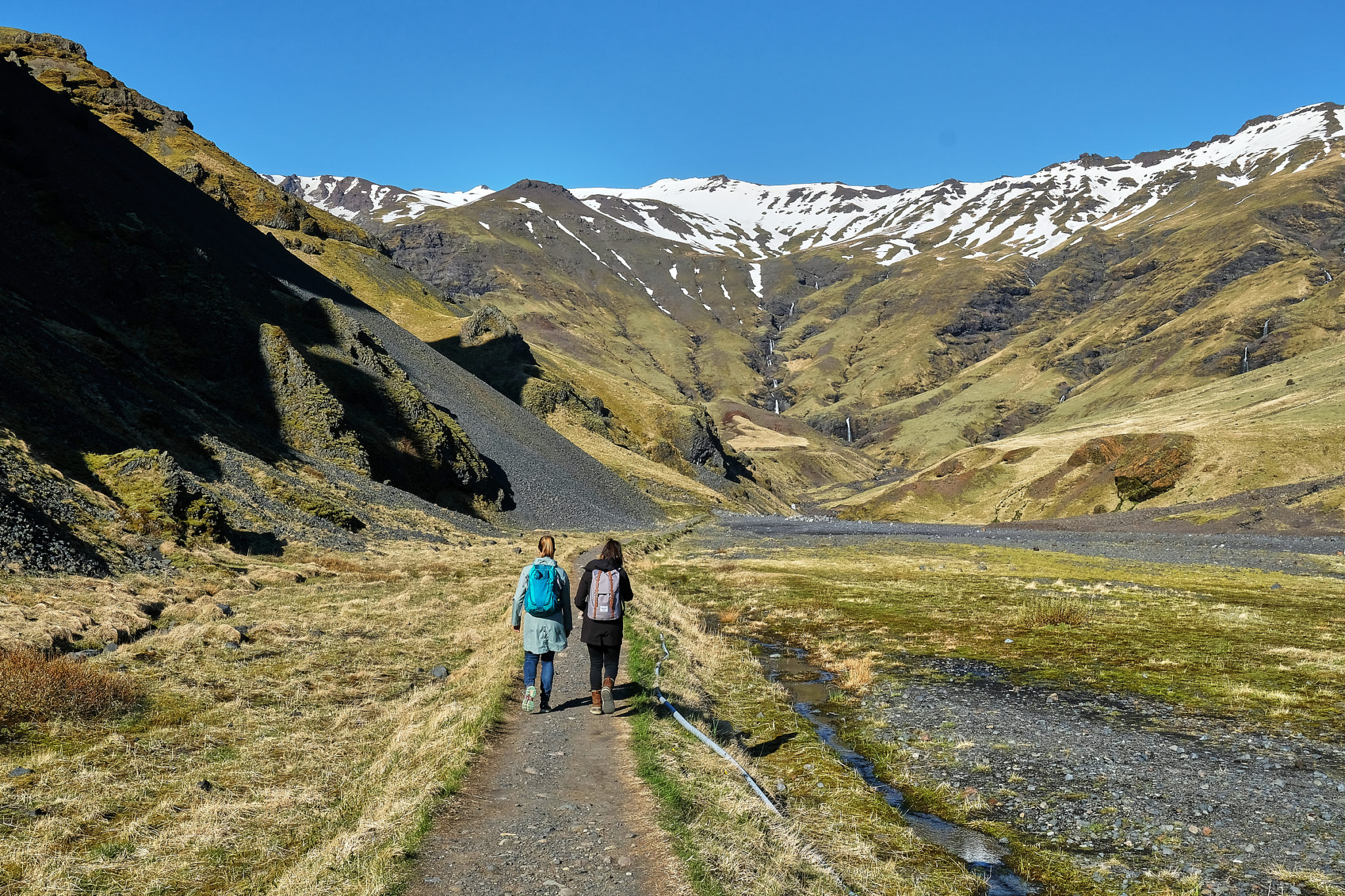 People hiking to geothermal natural pool Seljavallalaug on south cost of Iceland