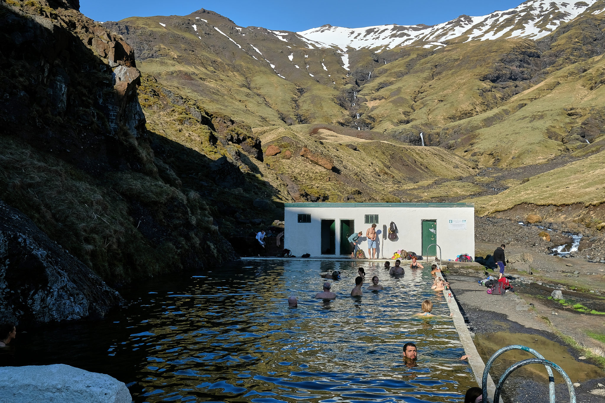 People enjoying geothermal natural pool Seljavallalaug on south coast of Iceland