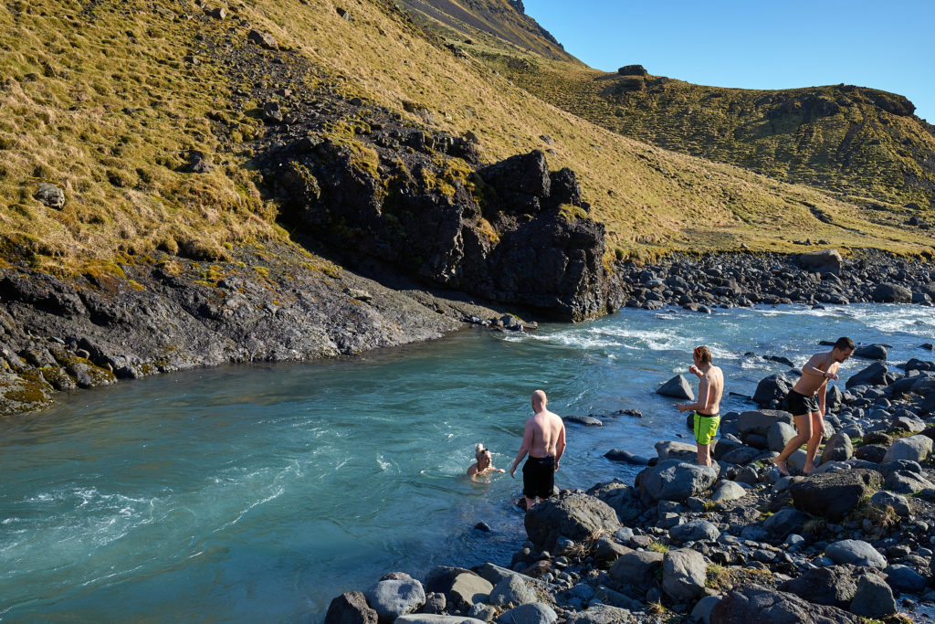 People bathing in Ice cold river by Seljavalllaug on south coast of Iceland